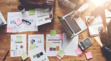 Business People Meeting Using Laptop Computer, Calculator, Notebook, Stock Market Chart Paper For Analysis Plans To Improve Quality Next Month. Conference Discussion Corporate Concept